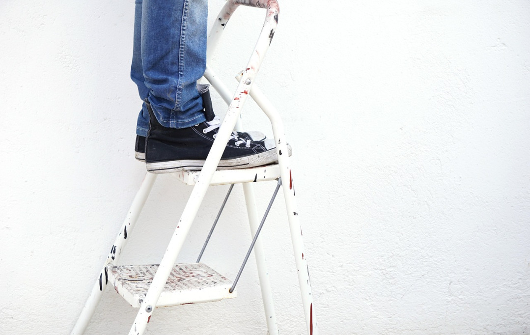 painter on ladder painting house exterior